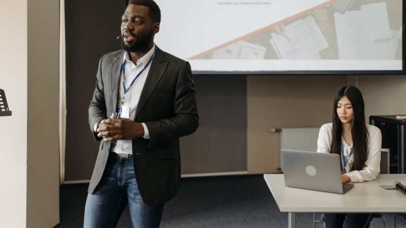 Personne présentant un pitch commercial percutant à un groupe de professionnels en réunion B2B